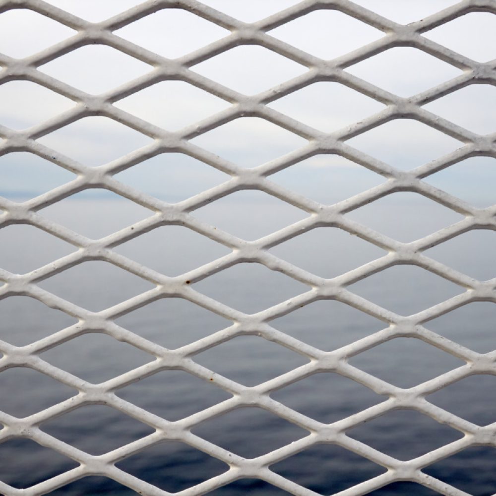 A white metal barrier with gradations of blue in the background.