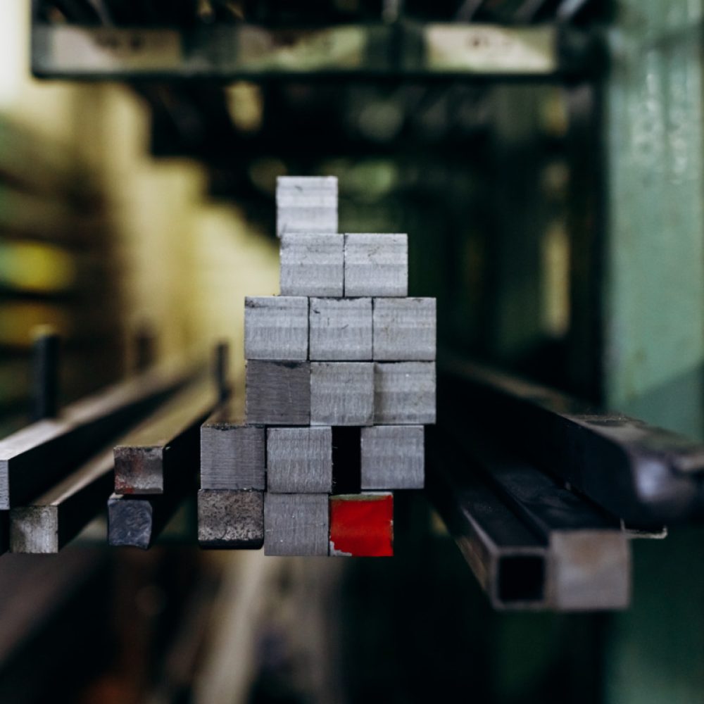 Steel square shaped rods in different sizes lying on storage shelves. Details of metallurgical plant. Close up, copy space.